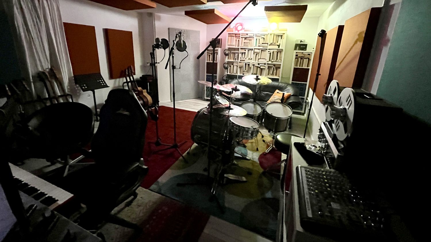 Gesamtansicht des Studios mit Keyboard, Gitarren, Schlagzeug und Bandmaschine
